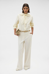 Profile view of model wearing the Oroton Scallop Tie Neck Shirt in Whipped Cream and 100% soft cotton fabric for Women .