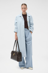 Profile view of model wearing the Oroton Essential Mac in Soft Smoke Blue and 77% cotton and 23% linen blend fabric for Women .