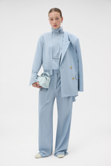 Profile view of model wearing the Oroton Pleat Detail Pant in Twilight Blue and 95% wool and 5% Lycra blend fabri for Women .