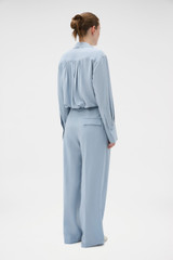 Profile view of model wearing the Oroton Pleat Detail Pant in Twilight Blue and 95% wool and 5% Lycra blend fabri for Women .