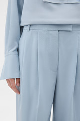 Profile view of model wearing the Oroton Pleat Detail Pant in Twilight Blue and 95% wool and 5% Lycra blend fabri for Women .