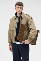 Profile view of model wearing the Oroton Paxton Suede Tote in Husk Brown and Premium Grade A velvet-finish cow suede leather for Men .
