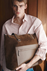 Profile view of model wearing the Oroton Paxton Suede Tote in Husk Brown and Premium Grade A velvet-finish cow suede leather for Men .