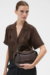 Profile view of model wearing the Oroton Mica Bowler in Dark Chocolate and Premium pebble grain leather for Women .