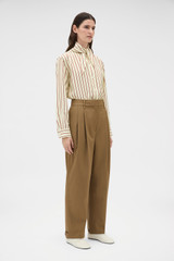 Profile view of model wearing the Oroton Tapered Pleat Pant in Dark Rye and 97% wool and 3% spandex blend fabric for Women .