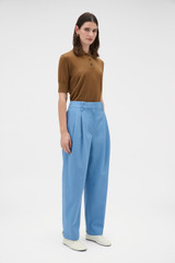 Profile view of model wearing the Oroton Tapered Pleat Pant in Porcelain Blue and 97% wool and 3% spandex blend fabric for Women .