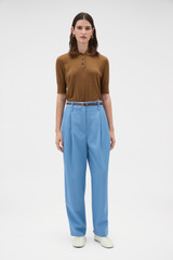 Profile view of model wearing the Oroton Tapered Pleat Pant in Porcelain Blue and 97% wool and 3% spandex blend fabric for Women .