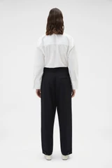 Profile view of model wearing the Oroton Tapered Pleat Pant in Black and 100% wool fabric for Women .
