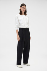 Profile view of model wearing the Oroton Tapered Pleat Pant in Black and 100% wool fabric for Women .
