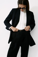 Profile view of model wearing the Oroton Tapered Pleat Pant in Black and 100% wool fabric for Women .
