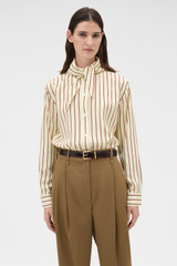 Profile view of model wearing the Oroton Stripe Tie Neck Shirt in Lemon/Rich Red and 100% silk habotai fabric for Women .