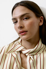 Profile view of model wearing the Oroton Stripe Tie Neck Shirt in Lemon/Rich Red and 100% silk habotai fabric for Women .