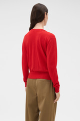 Profile view of model wearing the Oroton Deep V Knit in Poppy and 90% merino wool and 10% silk blend fabric for Women .