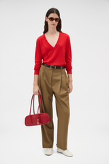 Profile view of model wearing the Oroton Deep V Knit in Poppy and 90% merino wool and 10% silk blend fabric for Women .
