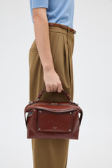 Profile view of model wearing the Oroton Mica Burnished Leather Bowler in Dark Chestnut and Smooth, vegetable-tanned leather for Women .