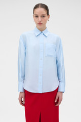 Profile view of model wearing the Oroton Silk Long Sleeve Shirt in Cloud Blue and 100% SILK DUPION for Women .