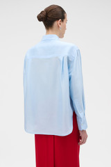 Profile view of model wearing the Oroton Silk Long Sleeve Shirt in Cloud Blue and 100% silk dupion fabric for Women .