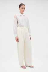 Profile view of model wearing the Oroton Barrel Leg Tuxedo Pant in Soft Cream and 100% linen fabric for Women .