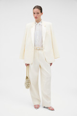 Profile view of model wearing the Oroton Barrel Leg Tuxedo Pant in Soft Cream and 100% linen fabric for Women .