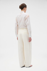 Profile view of model wearing the Oroton Barrel Leg Tuxedo Pant in Soft Cream and 100% linen fabric for Women .