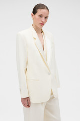 Profile view of model wearing the Oroton Oversized Tuxedo Jacket in Soft Cream and 100% linen fabric for Women .