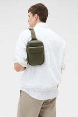 Profile view of model wearing the Oroton Oscar Pebble Crossbody in Forest Green and Premium pebble leather for Men .