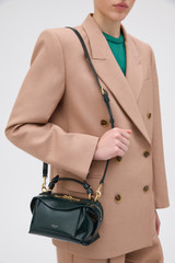 Profile view of model wearing the Oroton Mica Crackle Mini Bowler in Shade Green and Premium crackle leather for Women .