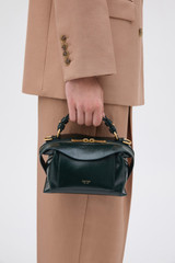 Profile view of model wearing the Oroton Mica Crackle Mini Bowler in Shade Green and Premium crackle leather for Women .
