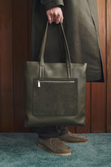 Profile view of model wearing the Oroton Oscar Pebble Tote in Forest Green and Premium pebble leather for Men .