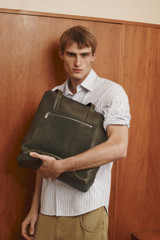 Profile view of model wearing the Oroton Oscar Pebble Tote in Forest Green and Premium pebble leather for Men .