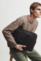 Profile view of model wearing the Oroton Nicholas Smooth Double Zip Briefcase in Black and Soft nappa cow leather for Men .