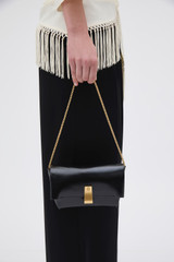 Profile view of model wearing the Oroton Etta Crackle Mini Clutch in Black and Soft crackle leather for Women .