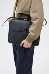 Profile view of model wearing the Oroton Nicholas Smooth Satchel Messenger in Black and Soft nappa cow leather for Men .