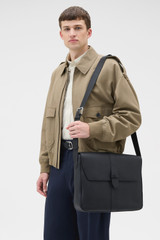 Profile view of model wearing the Oroton Nicholas Smooth Satchel Messenger in Black and Soft nappa cow leather for Men .