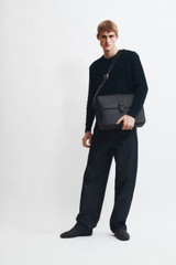 Profile view of model wearing the Oroton Nicholas Smooth Satchel Messenger in Black and Soft nappa cow leather for Men .