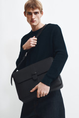 Profile view of model wearing the Oroton Nicholas Smooth Satchel Messenger in Black and Soft nappa cow leather for Men .