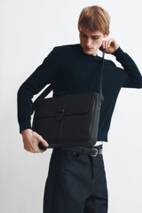 Profile view of model wearing the Oroton Nicholas Smooth Satchel Messenger in Black and Soft nappa cow leather for Men .