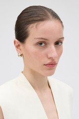 Profile view of model wearing the Oroton Banks Huggie in Gold and Premium brass material for Women .