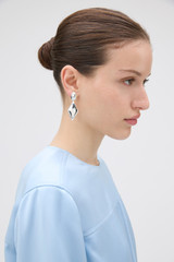 Profile view of model wearing the Oroton Banks Drop Earrings in Bright Silver and Premium brass material for Women .