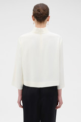 Profile view of model wearing the Oroton Scarf Detail Top in Soft Cream and 96% viscose and 4% spandex blend fabric for Women .