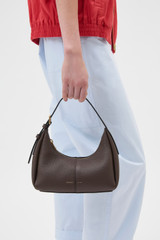 Profile view of model wearing the Oroton Dorit Mini Hobo in Coffee Bean and Premium pebble leather for Women .