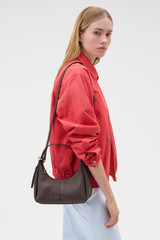 Profile view of model wearing the Oroton Dorit Mini Hobo in Coffee Bean and Premium pebble leather for Women .