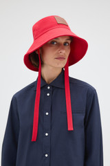 Profile view of model wearing the Oroton Nell Bucket Hat in Market Red and 100% cotton canvas fabric for Women .
