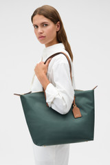 Profile view of model wearing the Oroton Lilly Nylon Light Weight Tote Bag in Evergreen/Cognac and Nylon material for Women .