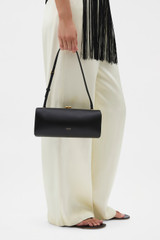 Profile view of model wearing the Oroton Penny Satin Clutch in Black and Satin fabric for Women .