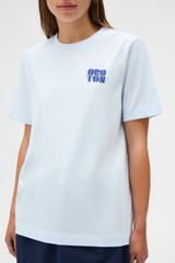 Profile view of model wearing the Oroton Maggie Graphic Tee in Pale Blue and 100% cotton single jersey fabric for Women .