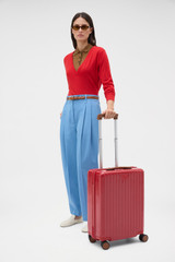 Profile view of model wearing the Oroton Jet Carry On Roller Case in Dark Ruby and Durable polycarbonate shell for Women .