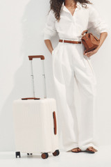 Profile view of model wearing the Oroton Jet Carry On Roller Case in Warm White and Durable polycarbonate shell for Women .