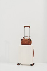 Profile view of model wearing the Oroton Jet Carry On Roller Case in Warm White and Durable polycarbonate shell for Women .
