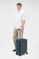 Profile view of model wearing the Oroton Jet Carry On Roller Case in Dark Evergreen and Durable polycarbonate shell for Women .